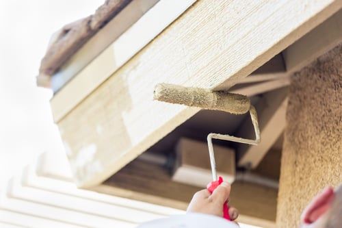 Painter rolling fresh paint onto exterior trim